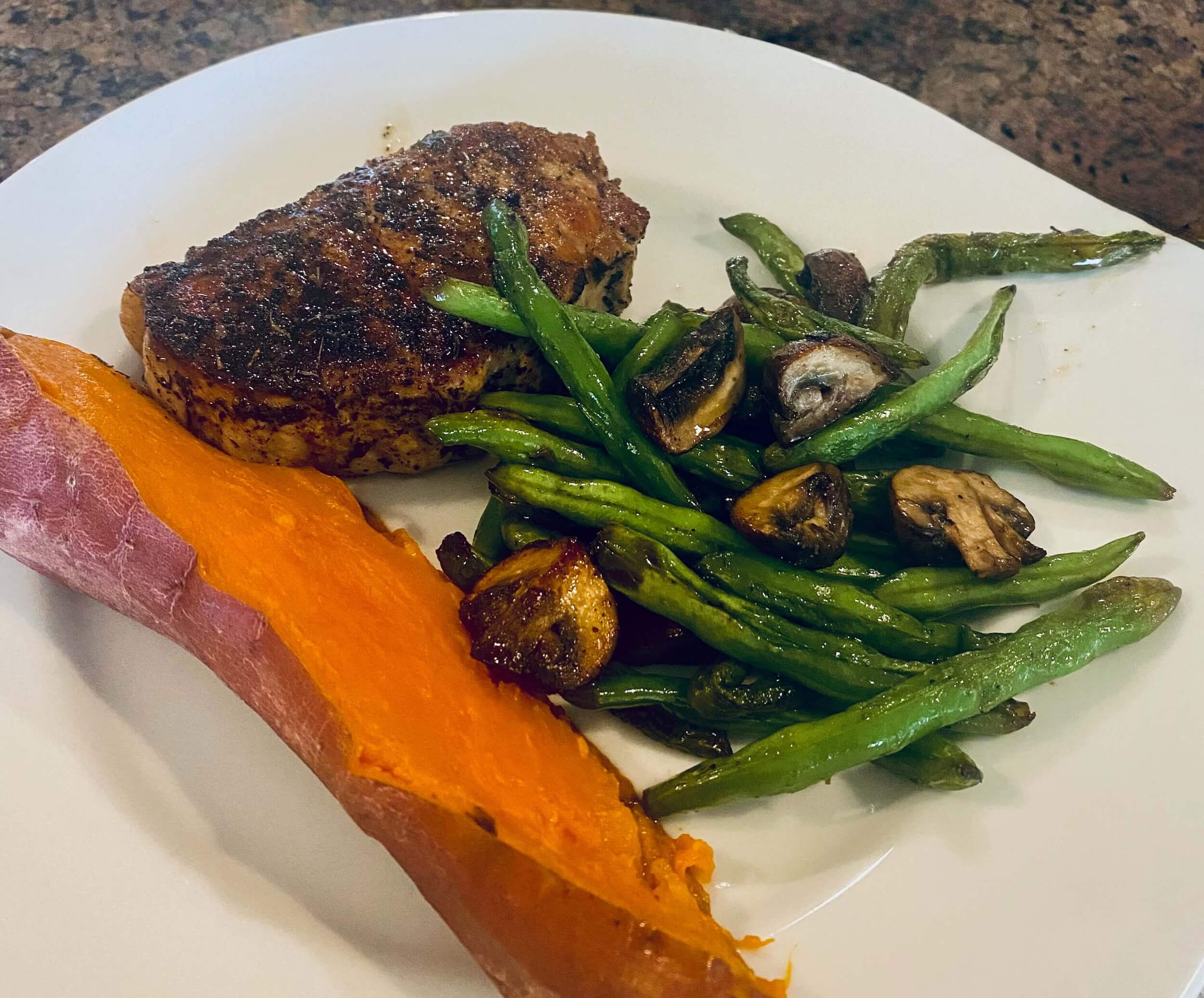 Colorful plate with sweet potato, green beans, mushrooms and meat on a table